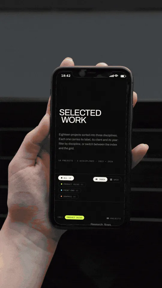 Mockup fotográfico: una mano sostiene un teléfono con el archivo de trabajo del portfolio desplazándose, de las filas de desarrollo front-end a la sección de diseño gráfico